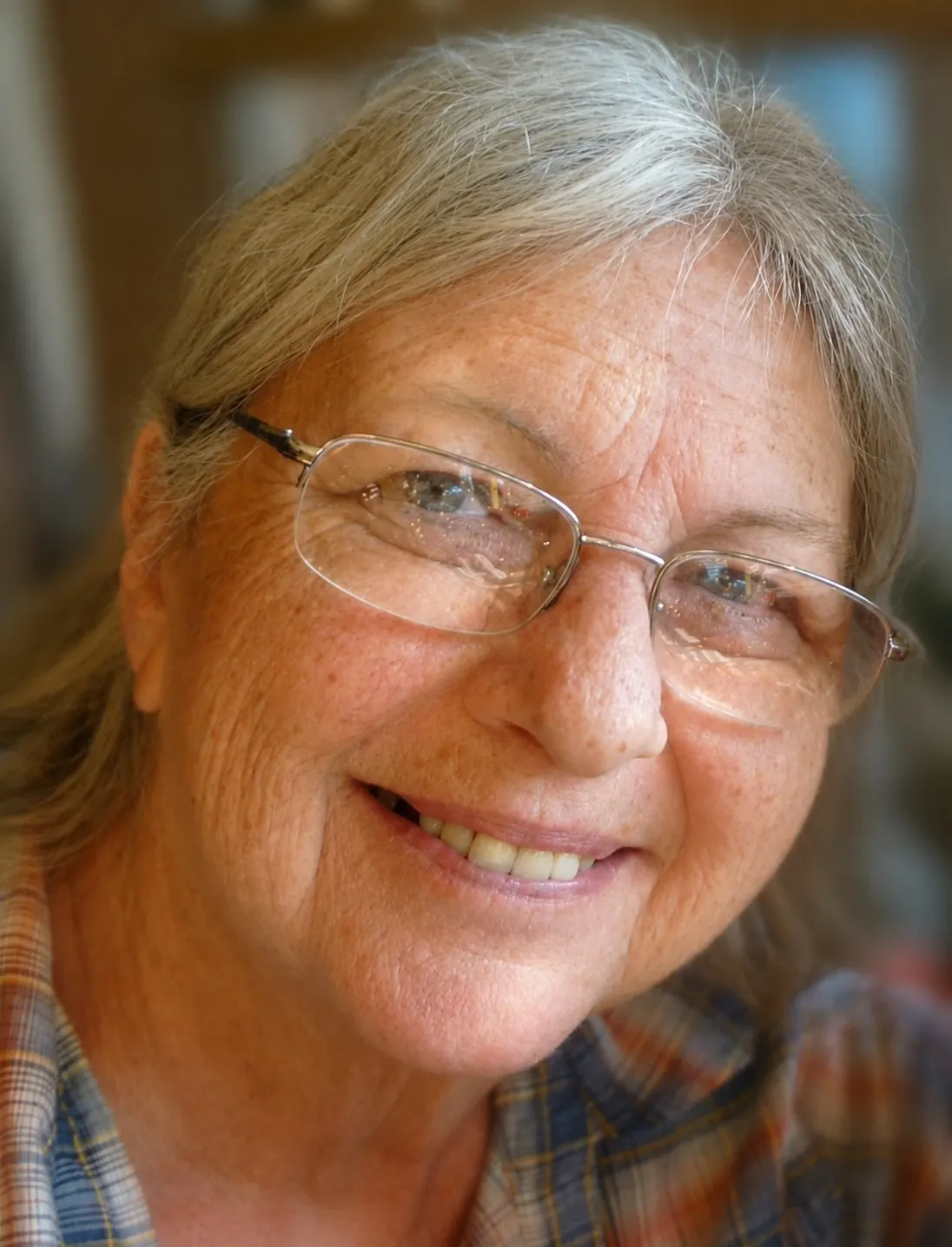 Portrait of Cynthia, a lifelong pianist and piano teacher, smiling in glasses, honored by Harmony & Healing